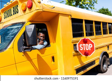 smiling mature african american bus driver looking out window and gesturing