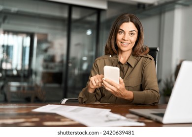 Smiling mature business woman executive using mobile phone working in office. Happy middle aged businesswoman holding smartphone, professional female executive looking camera with cellphone. Portrait. - Powered by Shutterstock