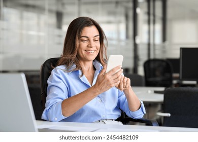 Smiling mature business woman executive using mobile phone working in office. Happy middle aged businesswoman holding smartphone, professional female executive looking at cellphone at workplace. - Powered by Shutterstock