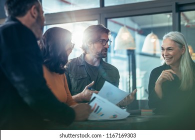 Smiling Mature Business Woman Talking With Colleagues During Meeting. Group Of People Standing Around A Table And Discussing Work.