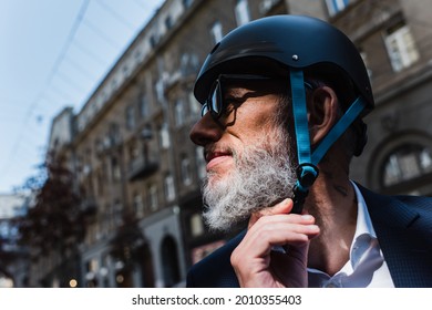 smiling and mature businessman adjusting helmet outside - Powered by Shutterstock