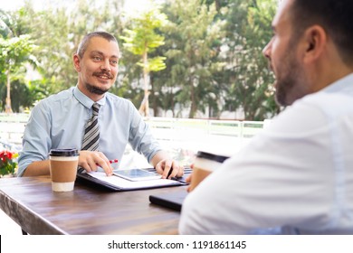 Smiling mature businessman having meeting with partner at cafe. Caucasian hr manager talking to male candidate at cafe. Recruitment or partnership concept