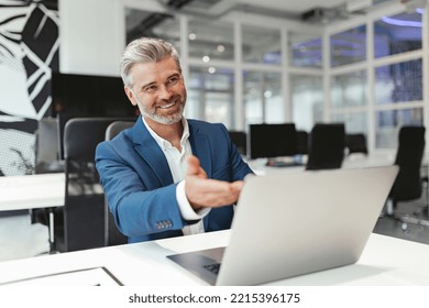 Smiling Mature Businessman Working With Laptop While Sitting In Modern Coworking