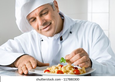 Smiling mature chef preparing an Italian dish of pasta with satisfaction