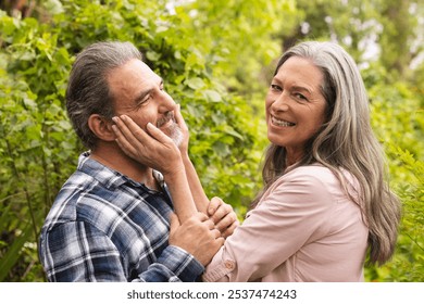 Smiling mature couple enjoying tender moment together in lush garden, outdoors. Romance, affection, togetherness, leisure, outdoors, greenery - Powered by Shutterstock