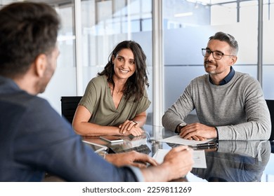 Pareja madura sonriente reuniéndose con un gerente de banco para inversiones. Mujer adulta media con marido escuchando al empresario durante una reunión en la sala de conferencias. Asesora de préstamos de la pareja de edad media.