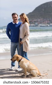 Smiling Mature Couple On The Beach With Their Dog