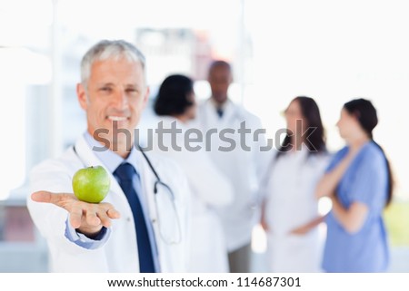 Smiling mature doctor holding an apple