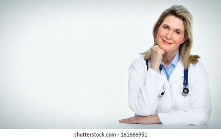 Smiling mature doctor woman. Over gray background.