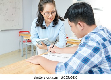 Smiling Mature Female Math Teacher Helping Student To Solve Equation