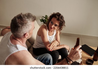 Smiling Mature Glam Rock Couple Talking, Drinking Beer And Smoking At Home