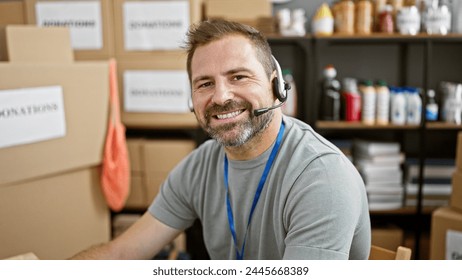 Smiling mature hispanic man with grey hair wearing a headset in a donation center warehouse - Powered by Shutterstock