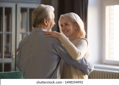 Smiling Mature Husband And Wife Relax Dancing Celebrating Wedding Anniversary At Home, Happy Elderly Man And Woman Couple Waltz Sway Enjoy Romantic Tender Moment Together, Relationships Goal Concept