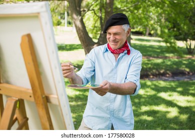 Smiling mature man painting on canvas in the park - Powered by Shutterstock