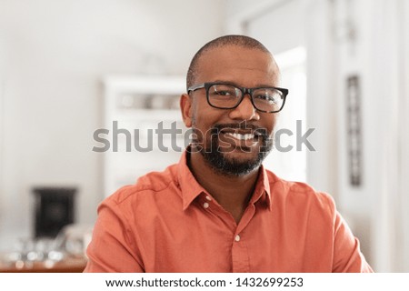 Smiling mature man wearing spectacles looking at camera. Portrait of black confident man at home. Successful entrepreneur feeling satisfied.