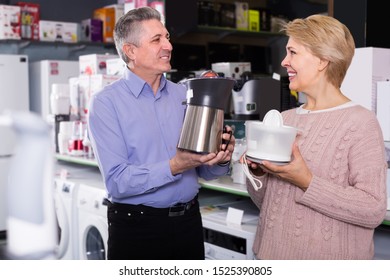 Smiling Mature Married Couple In Shopping Center Buys Small Kitchen Household Appliances For Their Home