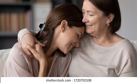 Smiling mature mother hugging adult daughter close up, expressing love and care, family enjoying tender moment, happy young woman and middle aged mum cuddling, two generations good relations