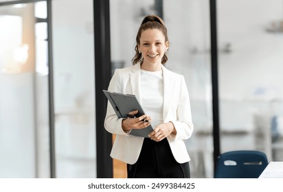 Smiling mature professional business woman manager, older happy female executive or lady entrepreneur holding fle folder standing in office at work, looking at camera. - Powered by Shutterstock