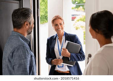 Smiling mature social counselor meeting mature couple at home. Happy multiethnic man and latin woman greeting agent at home standing near door. Successful social worker consultant on the doorstep. - Shutterstock ID 2018571416