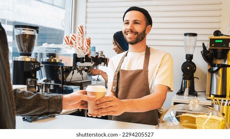 Smiling mature waiter giving take away coffee to man at cafeteria. Barista holding coffee to go in paper cup. Preparation, service concept - Powered by Shutterstock