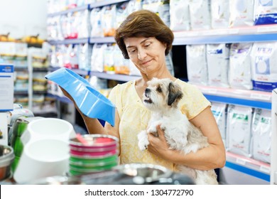 Smiling  Mature Woman Choosing Pet Food Bowl For Her Puppy In Pet Supplies Store