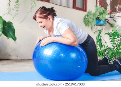 Smiling mature woman exercising at home with a stability ball, embracing a healthy and active lifestyle. Perfect representation of fitness, wellness, and self-care for older adults. - Powered by Shutterstock