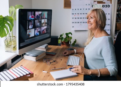 Lächelnde reife Frau mit Videoanruf über Computer im Heimbüro. Online-Team Treffen Video-Konferenz Anruf von zu Hause aus. Attraktive Geschäftsfrau Telearbeit. Business-Videokonferenzen. 