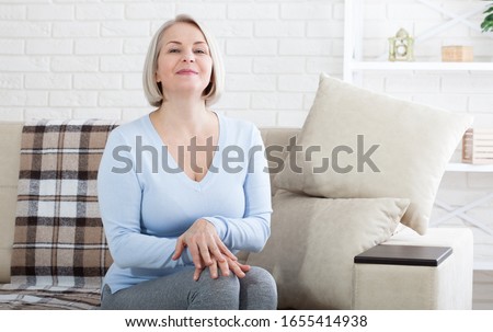 Smiling mature woman sitting on her sofa relax