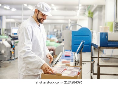 A smiling meat factory worker packing and controlling meat in boxes ready for transportation. - Powered by Shutterstock