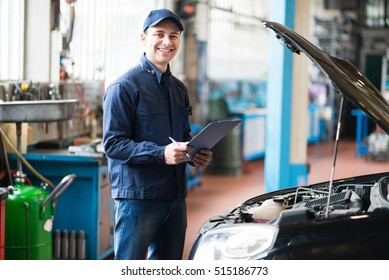 Smiling Mechanic Holding A Clipboard In Front Of A Car