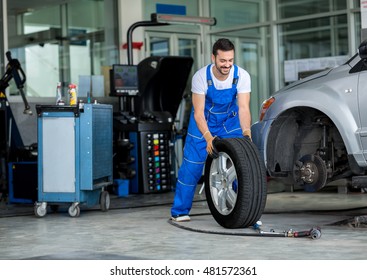 Smiling mechanic pushes the tire in a workshop - Powered by Shutterstock