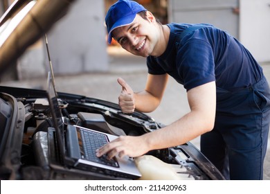 Smiling Mechanic Using A Laptop Computer To Check A Car Engine