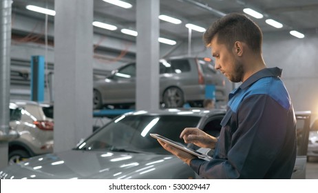 Smiling mechanic using a tablet pc at the repair garage service
