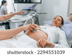 Smiling, medical procedure. Pregnant woman is lying down in the hospital, doctor does ultrasound.