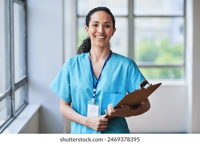 Smiling Medical Professional in Scrubs Holding a Clipboard in Hospital Setting - Powered by Shutterstock