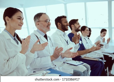 Smiling Medical Workers Applauding While Having Meeting In Conference Room Stock Photo