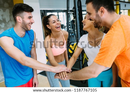 Smiling men and women doing high five in gym