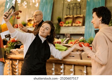 Smiling merchant and customer taking photos on smartphone, showcasing freshly harvested fruits and veggies. Female vendor using mobile device for pictures while shopper purchases organic bio tomatoes. - Powered by Shutterstock