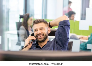 Smiling mid adult businessman talking on phone in office