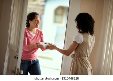 Smiling Mid Adult Woman Greeting Her Neighbor With A Casserole Dish.