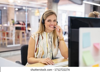 Smiling mid woman working as customer support operator with headset in a call center. Portrait of happy sales agent sitting at desk and looking at camera. Customer care support service representative.