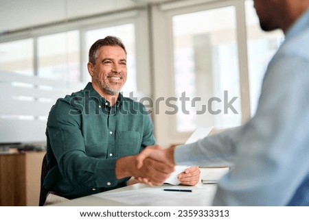 Smiling middle aged business man handshaking partner making partnership collaboration agreement at office meeting, hr manager and new worker shake hands recruiting at job interview. Welcome onboarding