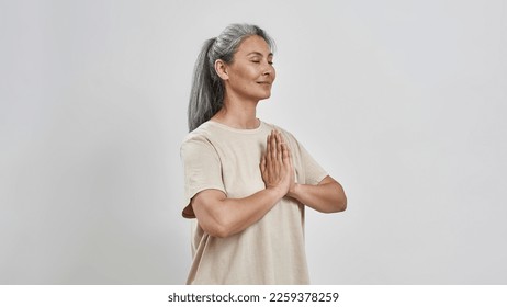 Smiling middle aged caucasian woman with closed eyes practicing yoga. Modern healthy lifestyle. Mental health and harmony. Female wearing sportswear. Isolated on white background in studio. Copy space - Powered by Shutterstock