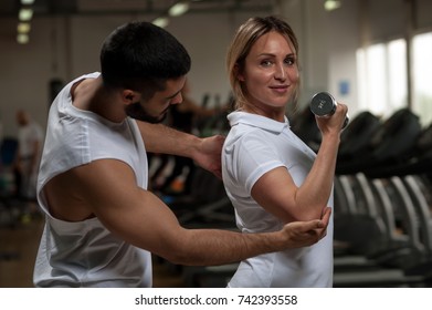 Smiling Middle Aged Caucasian Woman Doing Weight Exercise With Personal Trainer. Blonde Female Exercising With Assistance Of Fitness Coach. Healthy Lifestyle, Fitness And Sports Concept.