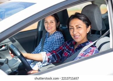 Smiling Middle Aged Colombian Woman Driving Car With Girl In Passenger Seat..