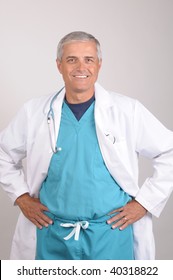 Smiling Middle Aged  Doctor Wearing Scrubs And Lab Coat With His Hands On His Hips