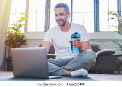 Smiling Middle Aged Man Using Laptop And Drinking Water While Having Break During Workout At Home