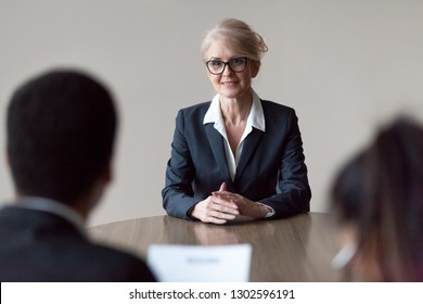 Smiling middle aged senior female job applicant listening to hr questions making first impression at interview, recruiters interviewing older mature candidate, recruitment, age and employment concept