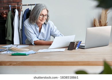 Smiling middle aged stylish woman fashion designer holding sketches in studio office. Mature old adult elegant grey-haired lady small business owner creating new fashion design cloth in atelier. - Shutterstock ID 1838518861