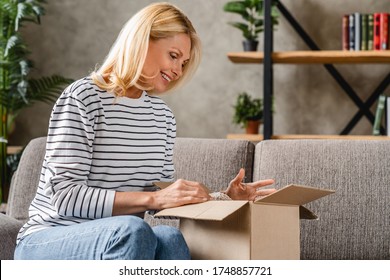 Smiling Middle Aged Woman Customer Receive Post Shipment Parcel At Home